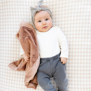 Saranoni Lush Mini Blanket - Rosy
Baby holding a brown blanket wearing a white shirt, gray pants, and a gray headband on a checkered background.