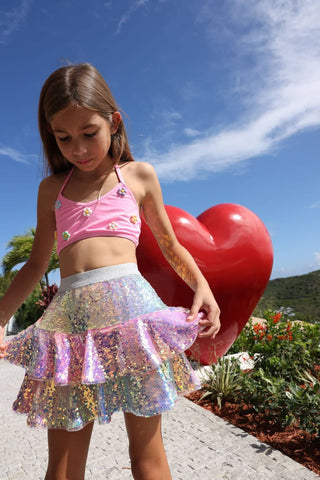 Lola and The Boys Sequin Ombre Ruffle Skirt
Young girl in a pink top and sequin skirt holding a heart-shaped balloon outdoors.