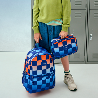 State Bags Kane Backpack - Gradient Checkerboard
State Bags Rodgers Lunch Box -  Gradient Checkerboard
Person holding a blue checkered backpack and lunch bag in front of gray lockers.