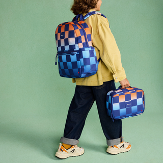 State Bags Kane Backpack - Gradient Checkerboard
State Bags Rodgers Lunch Box -  Gradient Checkerboard
Person wearing a blue and orange checkered backpack and holding a matching suitcase on a green background