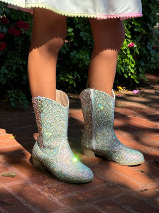 Lola and The Boys Silver Crystal Cowgirl Boots
Children's glittery boots on a child standing on a brick surface with plants in the background.