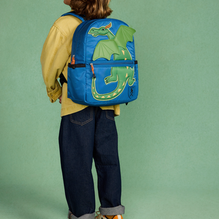 State Bags Kane Backpack - Dragon
A child viewed from behind wearing a bright blue backpack with a large green dragon graphic on the back, paired with a yellow shirt and dark jeans, against a solid green studio background.