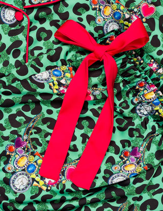 Sunshine Society Kids Silky Short Sleeve Short Set - Gilded Leopard
A close-up of a green leopard-print fabric with a colorful patchwork print and a prominent bright red satin bow tied at the waist.