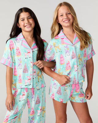 Sunshine Society Kids Silky Short Sleeve Short Set - Prancer
Two girls modeling matching short-sleeve pajama sets with a pastel unicorn and castle print on a mint green background, against a light gray studio backdrop.