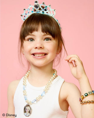Super Smalls Disney Frozen Headband & Jewelry Kit
A young girl smiling and wearing a Disney-themed jewelry set, including a tiara, pearl necklace with a princess pendant, and beaded bracelets, against a solid pink background.