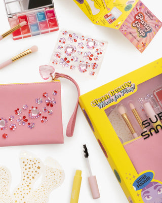 Super Smalls Party Prep Beauty Kit
Makeup set with pink pouch, brushes, and decorative elements on a white background