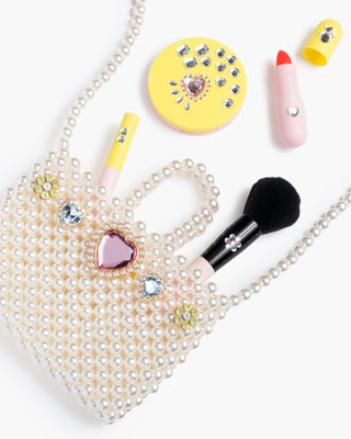 Super Smalls Pearl of the Party Handbag
Makeup items including a brush, compact mirror, and lip gloss with decorative elements on a white background.