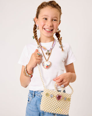 Super Smalls Pearl of the Party Handbag
Young girl holding a decorative handbag with a plain background