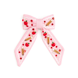 Sweet Wink Apple Gemstone Bow Clip
Pink bow hair clip with red apple and gold pencil designs on a white background