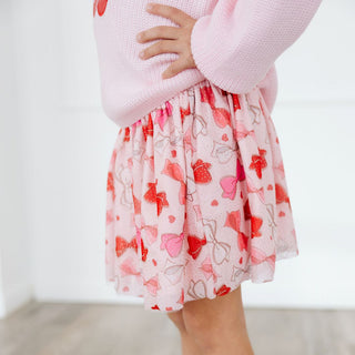 Sweet Wink Bow Love Valentine's Day Tutu
Child wearing a pink sweater and floral skirt on a white background