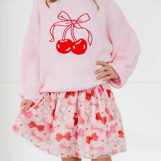 Sweet Wink Bow Love Valentine's Day Tutu
Child wearing a pink sweater with red cherries and a matching skirt with bow pattern on a white background