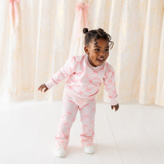 Sweet Wink Bow Trellis Sweatshirt & Flare Legging Set
Child wearing a pink flamingo pajama set against a white curtain background