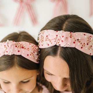 Sweet Wink Candy Cane Christmas Gemstone Headband - Womens 
Two children wearing pink headbands with decorative elements against a blurred background.
