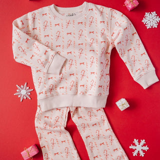 Sweet Wink Candy Cane Lane Christmas Sweatshirt & Flare Legging Set
Children's pajama set with candy cane and bow pattern on a red background with snowflakes and gift boxes.