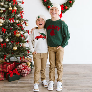 Sweet Wink Christmas Truck Patch Sweatshirt - Natural
Sweet Wink Merry Patch Christmas Knit Sweater
Two children standing in front of a decorated Christmas tree, wearing festive sweaters and hats.