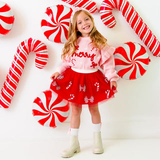 Sweet Wink Coquette Merry Christmas Knit Sweater
Young girl in a festive outfit with candy-themed decorations on a white background