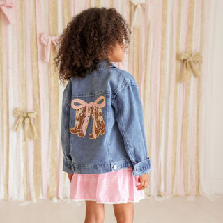 Sweet Wink Cowgirl Cutie Patch Western Denim Jacket
Child wearing a denim jacket with a bow design, standing in front of a curtain with ribbons.