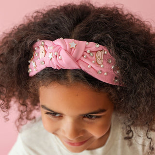 Sweet Wink Cowgirl Cutie Western Gemstone Headband
Young girl wearing a pink headband with decorative elements against a pink background