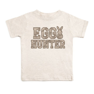 Sweet Wink Egg Hunter Camo Easter Short Sleeve T-Shirt - Natural Heather
Beige t-shirt with 'Egg Hunter' text and bunny graphic on a white background