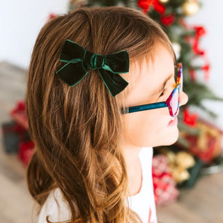 Sweet Wink Emerald Green Velvet Bow Christmas Clip
Child with green hair bow and colorful glasses in front of a decorated Christmas tree.