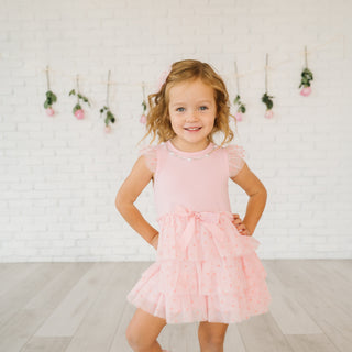 Sweet Wink Flocked Heart Valentine's Day Tiered Short Sleeve Tutu Dress
Young girl in a pink dress standing against a white brick wall with decorative flowers.