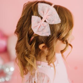 Sweet Wink Flocked Heart Valentine's Day Tulle Bow Headband
Child with pink hair bow against a pink background