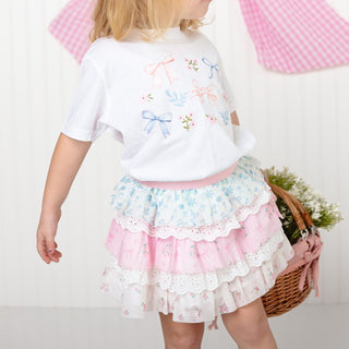 Sweet Wink Floral & Bow Watercolor Short Sleeve T-Shirt - White
Child wearing a white shirt with floral embroidery and a layered skirt, holding a basket.
