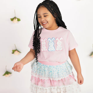 Sweet Wink Floral & Lace Tiered Tutu
Sweet Wink Floral Bunny Patch Easter Short Sleeve T-Shirt - Ballet
Young girl wearing a pink t-shirt with colorful bunny designs and a floral skirt.