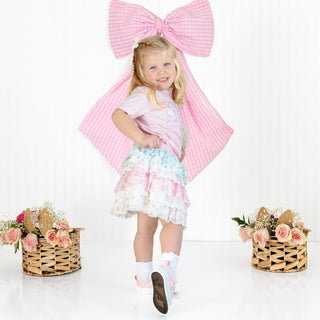 Sweet Wink Floral & Lace Tiered Tutu
Young girl in a pink cape and floral dress standing between two flower baskets on a white background