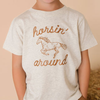 Sweet Wink Horsin' Around Western Short Sleeve T-Shirt 
Child wearing a t-shirt with a horse graphic and text on a beige background