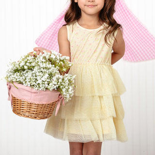 Sweet Wink Lemon Floral Tank Tutu Dress
Young girl in a yellow dress holding a basket of flowers against a pink and white checkered background