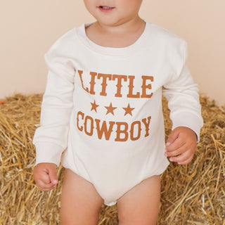 Sweet Wink Little Cowboy Western Long Sleeve Romper
Baby wearing a 'Little Cowboy' onesie standing on hay.