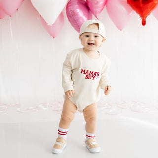 Sweet Wink Mama's Boy Varsity Patch Valentine's Day Long Sleeve Romper - Natural
Baby wearing a 'MAMA'S BOY' onesie with balloons in the background