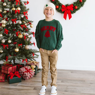 Sweet Wink Merry Patch Christmas Knit Sweater
Child wearing a green sweater with red text standing in front of a decorated Christmas tree.