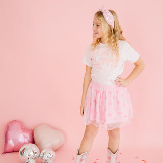 Sweet Wink Mini Sequin Hearts Valentine's Day Tutu
Young girl in a white t-shirt and pink tutu skirt with heart-shaped balloons on a pink background