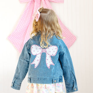 Sweet Wink Pearl and Gemstone Floral Bow Patch Denim Jacket
Child wearing a denim jacket with a large pink bow on the back, standing against a light background.