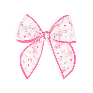 Sweet Wink Peony Floral Bow Clip
Decorative bow with pink trim and floral patterns on a white background