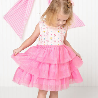 Sweet Wink Peony Floral Tank Tutu Dress
Young girl wearing a white top with colorful patterns and a pink ruffled skirt on a white background.