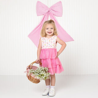 Sweet Wink Peony Floral Tank Tutu Dress
Young girl in a pink dress with a large pink bow in the background