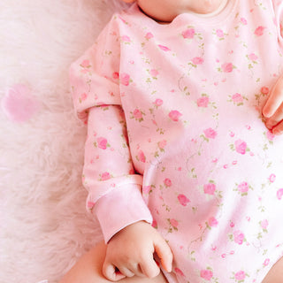 Sweet Wink Pink Rose Long Sleeve Romper - Pink
Baby in a pink floral outfit holding a hand on a soft pink background