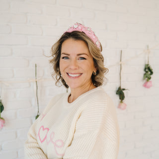 Sweet Wink Pink Valentine's Day Gemstone Headband - Large
Woman wearing a pink tiara and white sweater with pink hearts against a light brick wall.
