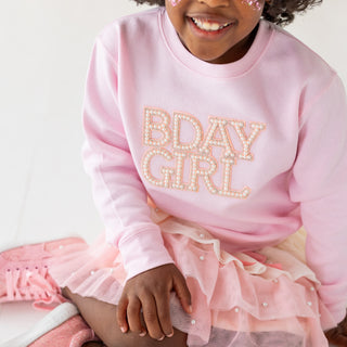 Sweet Wink Pretty Pearl Petal Tutu
Child wearing a pink 'BDAY GIRL' sweatshirt and matching skirt with sparkles.