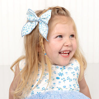 Sweet Wink Sky Floral Bow Clip
Sweet Wink Sky Floral Tank Tutu Dress
Young girl with a large blue bow in her hair wearing a matching outfit on a white background