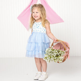 Sweet Wink Sky Floral Tank Tutu Dress
Young girl in a floral top and light blue skirt holding flowers and a pink bag on a white background