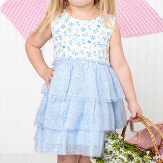 Sweet Wink Sky Floral Tank Tutu Dress
Child wearing a white dress with blue floral patterns and a matching blue skirt, holding a basket of flowers.