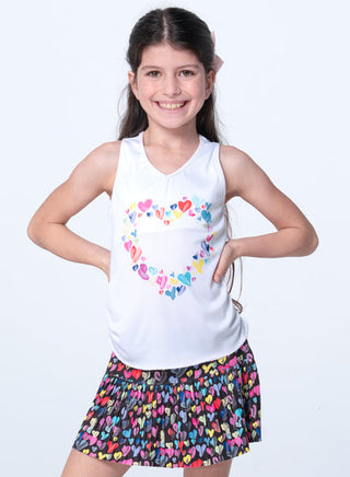 Lucky In Love Thumbprint Hearts Tank
Young girl wearing a white tank top with colorful heart design and a patterned skirt on a white background