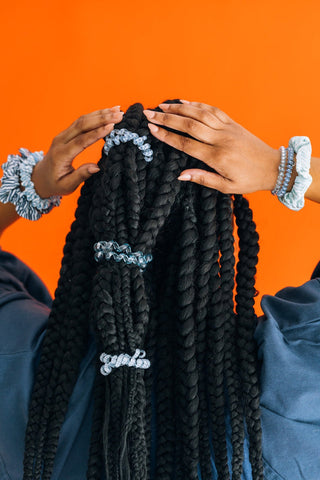 Teleties Hampton Bay Hair Ties - Large
Black braided hair extensions held by hands against an orange background