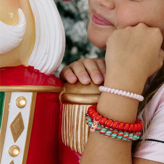 Teleties Spiral Hair Coils Mix Pack: You Crack Me Up Hair Ties
Person wearing colorful bracelets on a decorative figure with a blurred Christmas tree background