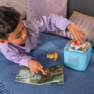 Disney Winnie the Pooh Toniebox 2 Full Play Set - Sky Blue
Child interacting with a toy book and a blue electronic device on a couch.