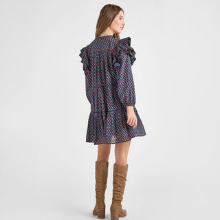 Pink Chicken Womens Kalani Dress - Navy Carnation Woman wearing a patterned dress with ruffled details and brown knee-high boots on a white background